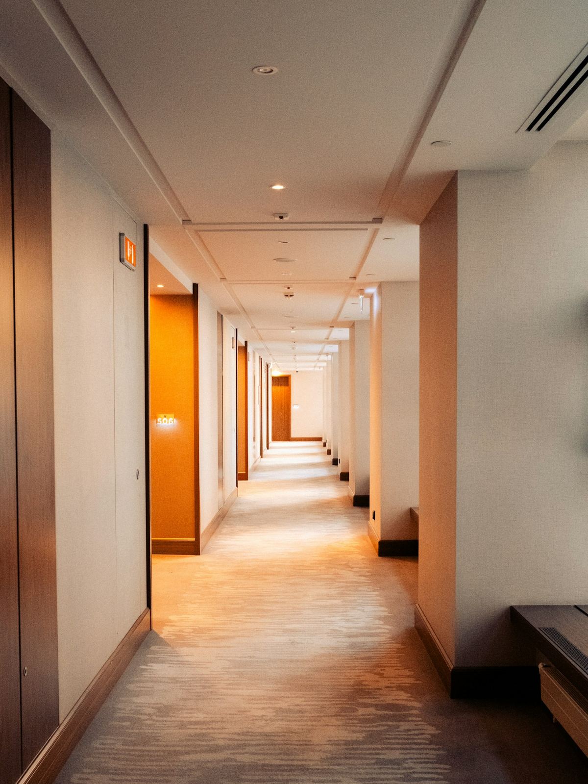 A long hotel hallway with warm directional lighting receding into perspective